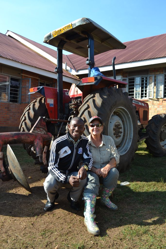 man and woman squat in front of farm tractor