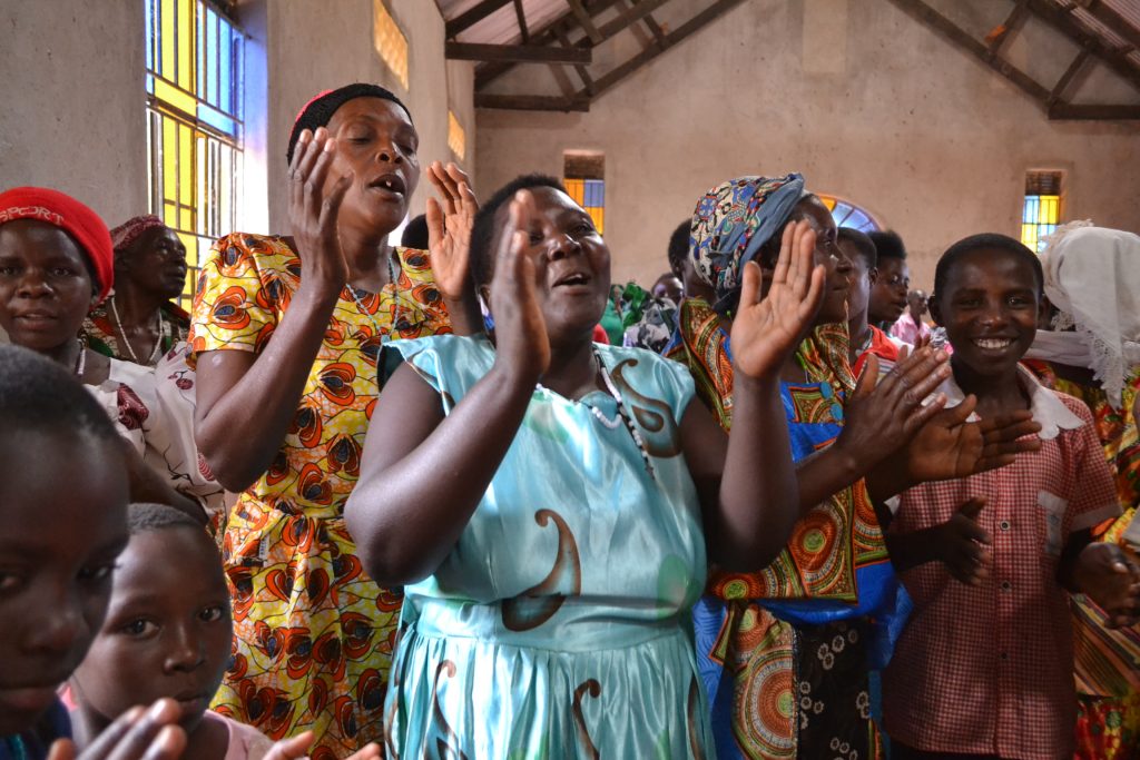 women in colorful clothing clapping and singing